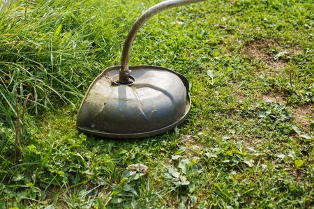 a man mows green grass with a trimmer outdoor