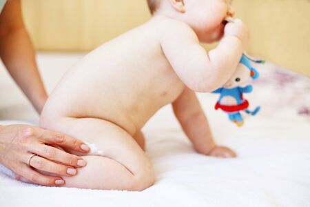 mother applying some cream by her hand to the baby ass for skin care. baby skin care with creamの写真素材