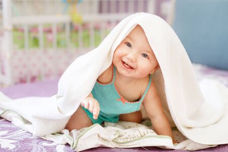 cute smiling baby looking at camera under a white towel.の写真素材