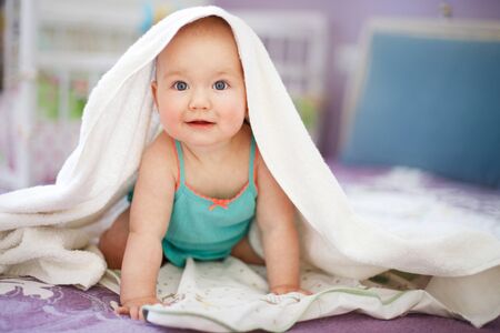 cute smiling baby looking at camera under a white towel.の写真素材