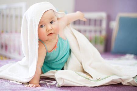 cute smiling baby looking at camera under a white towel.の写真素材