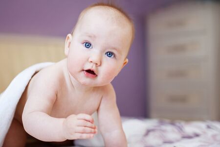 cute smiling baby looking at camera under a white towel.の写真素材
