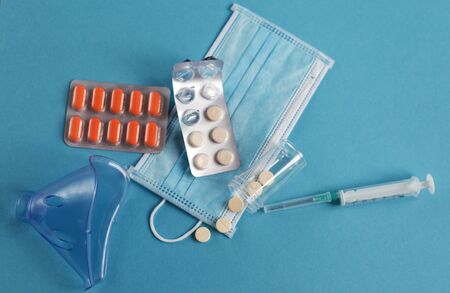 medical mask, syringe and tablets close on the blue background. Coronavirus, flu, respiratory disease concept. Horizontal orientation. Top view.の写真素材