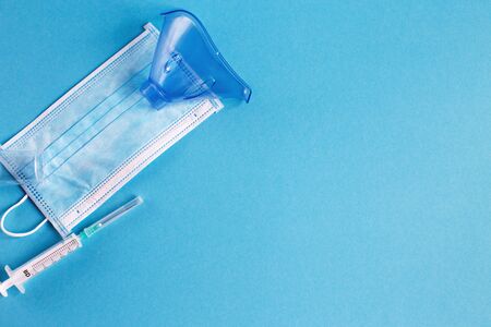 medical mask and syringe on the blue background. Coronavirus, flu, disease concept. Horizontal orientation. Top view.の写真素材