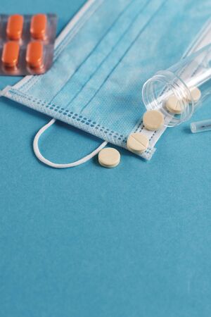 White medical mask, syringe, tablets and vials with medicine on the blue surface. Coronavirus, flu, respiratory disease concept. Horizontal orientation. Top view.の写真素材