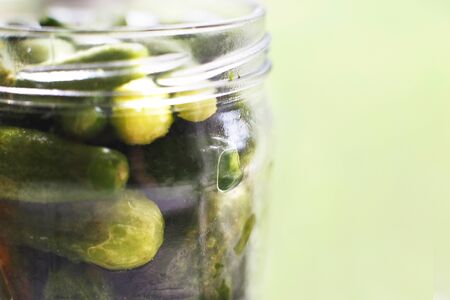 pickled cucumbers in the glass jar. gherkins cucumbers on a green background.の写真素材