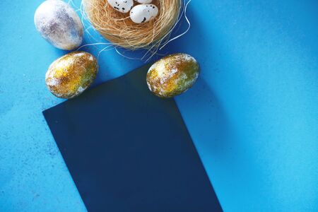 Gold and silver Easter eggs with nest on a blue background. Easter concept. Happy Easter. Copy spaceの写真素材