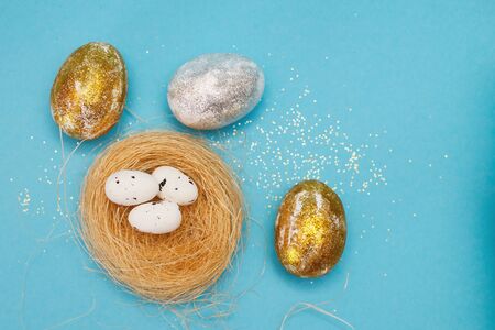 Gold and silver Easter eggs with nest on a blue background. Easter concept. Happy Easter. Copy spaceの写真素材