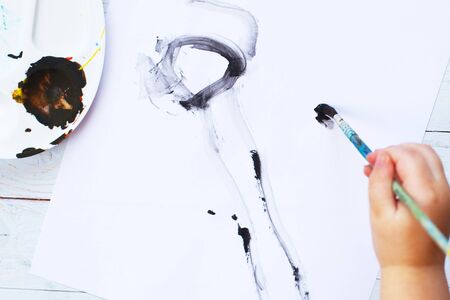 view from above. child draws a brush and paints top view. Flat lay art tools for painting.