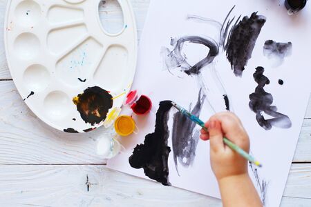 view from above. child draws a brush and paints top view. Flat lay art tools for painting.の写真素材