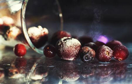 closeup frozen berries on the glass with reflection . frozen berries on a dark background macro. cranberries blueberries and cherriesの写真素材