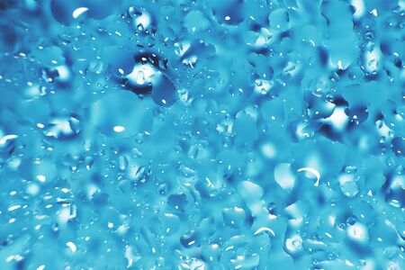 water drops on a blue background. Abstract blue background. Water drops on glass. Natural background toned in blue.の写真素材