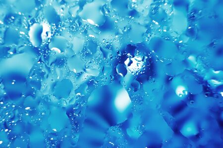 water drops on a blue background. Abstract blue background. Water drops on glass. Natural background toned in blue.の写真素材