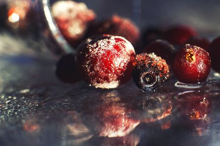 closeup frozen berries on the glass with reflection . frozen berries on a dark background macro. cranberries blueberries and cherriesの写真素材