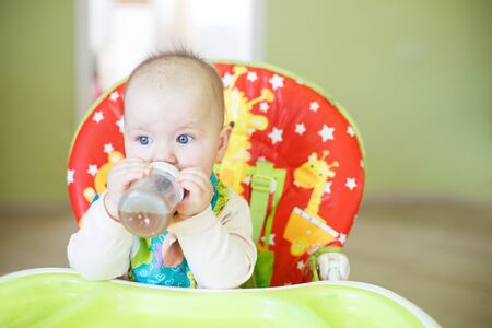 baby drinking from bottle sitting in the high chairの写真素材