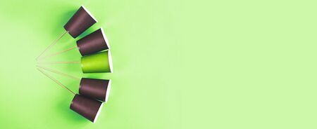 Eco-friendly disposable brown and green paper cups on a green background. Ecology concept. bannerの写真素材