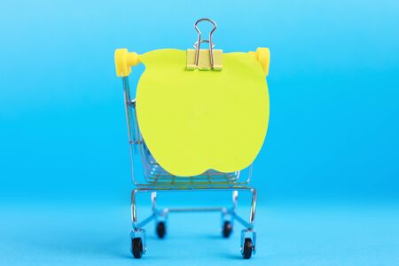 Note paper on shopping cart isolated on a blue backgroundの写真素材