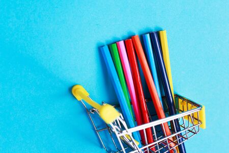 shopping cart with colored pencils on blue backgroundの写真素材