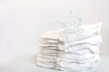 Baby diapers with toy carriage on a white backgroundの写真素材