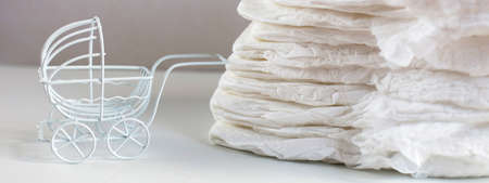 Baby diapers with toy carriage on a white backgroundの写真素材
