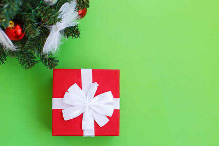 Christmas composition. Christmas gift, presrnt box and fir tree branches with toys on a green background. Top view. Flat lay.の写真素材