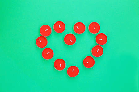 Shape of heart from red tea light candles. Red candles forming shape of heart on light wooden...