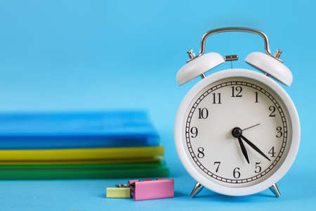 Textbooks and alarm clock on a blue background. Back to school. Library, education. Concept Education or businessの写真素材