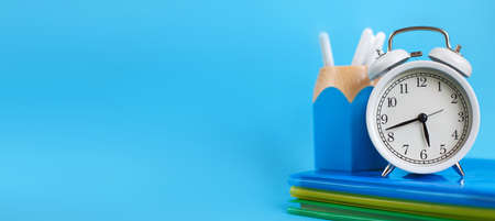 Textbooks and alarm clock on a blue background. Back to school. Library, education. Concept Education or business. bannerの写真素材