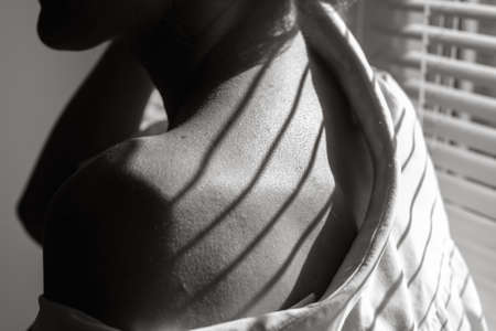 Sensual close up portrait of a beautiful young lady relaxing at the window. female shoulder close...