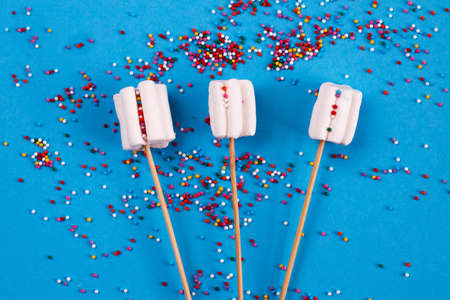 marshmallows composition on wooden skewers on a blue background. Flat lay, holiday concept. bouquet of sweetsの写真素材