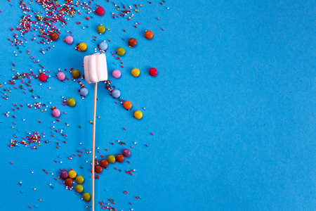 marshmallows composition on wooden skewers on a blue background. Flat lay, holiday concept....