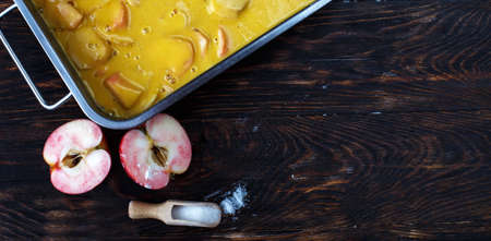 Making an apple pie. Raw dough in a baking dish, apple and sugar on the wooden background. bannerの写真素材