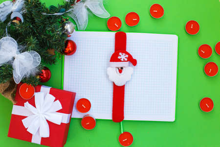 Christmas gift, presrnt box, many red candles, notepad for writing and fir tree branches with toys.の写真素材