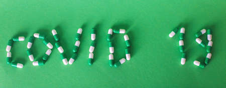 Inscription Covid 19 from letters made of pills on green background.の写真素材