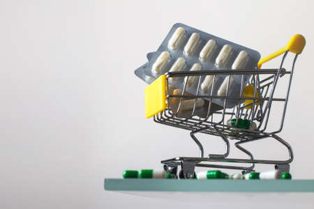 Shopping cart with medical pills on white mirror backgroundの写真素材