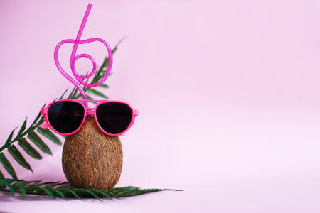 A coconut with straw and pink sunglasses on a pink background. Summer and trave concept. copy spaceの写真素材