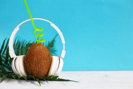 A coconut with straw and headphones on a blue background. Summer and trave concept. copy spaceの写真素材