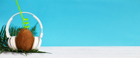 A coconut with straw and headphones on a blue background. Summer and trave concept. copy space....