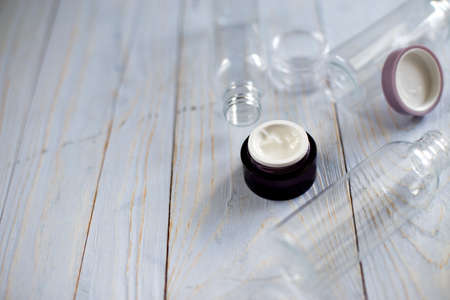 a jar of face cream with empty bottle and tube for detergent cleaning agent on natural light blue wooden backgroundの写真素材