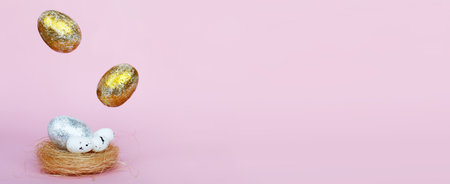 Gold and silver Easter eggs levitation to the nest on pink background. Easter concept. Copy spaceの写真素材