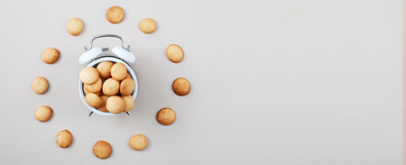 a sweet cookie in form of an alarm clock, time for breakfast or dessert concept. top view. mini pancakes backgroundの写真素材