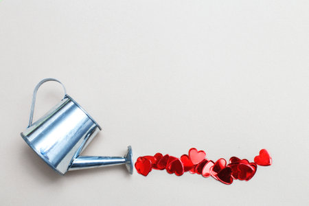 silver watering can flowers pouring hearts on light beige background. Valentines background, love, date conceptの写真素材