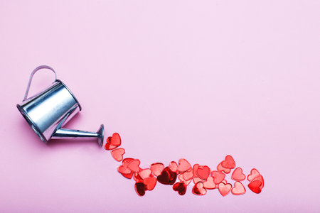 silver watering can flowers pouring hearts on pink background. Valentines background, love, date conceptの写真素材
