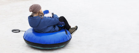 Family having fun on snow tube. mother with a kid is riding a tubing. Winter entertainment. people sliding downhill on tube. bannerの写真素材