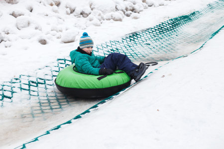 Child having fun on snow tube. Boy is riding a tubing. Winter entertainment. kid sliding downhill on a tubeの写真素材