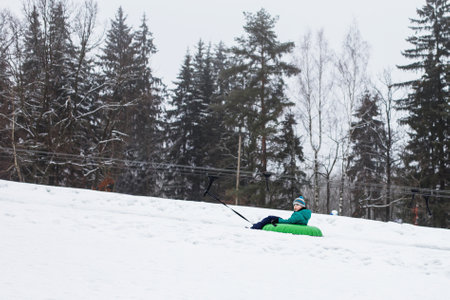 Child having fun on snow tube. Boy is riding a tubing. Winter entertainment. kid sliding downhill on a tube. ride a liftの写真素材