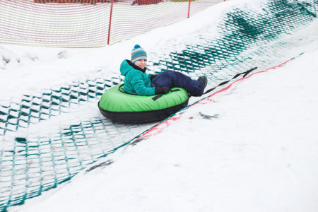 Child having fun on snow tube. Boy is riding a tubing. Winter entertainment. kid sliding downhill on a tubeの写真素材