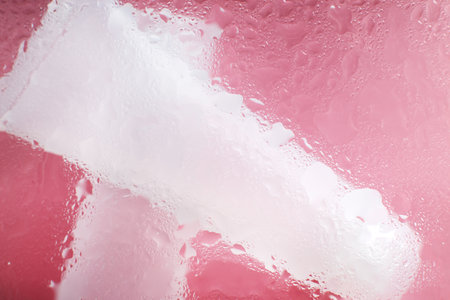 spa cosmetic products, transparent tube. Concept of natural moisturizing skin care products. Face and hand cream under a glass surface with water on a pink background.の写真素材