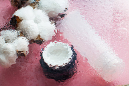 Concept of natural moisturizing skin care products. Face and hand cream under a glass surface with water on a pink background.の写真素材