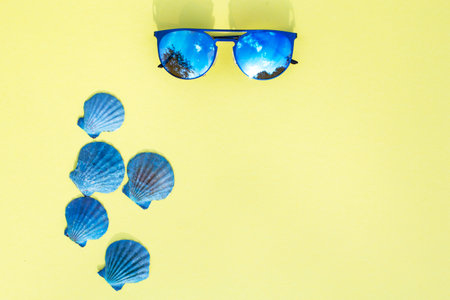 Travel vacation background. Sun glasses sea shells bright yellow background. Concept summer holidays.の写真素材